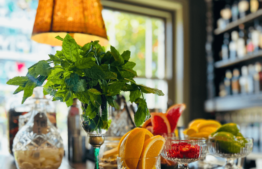 Bar top with fresh sliced fruit, herbs and an antique lamp